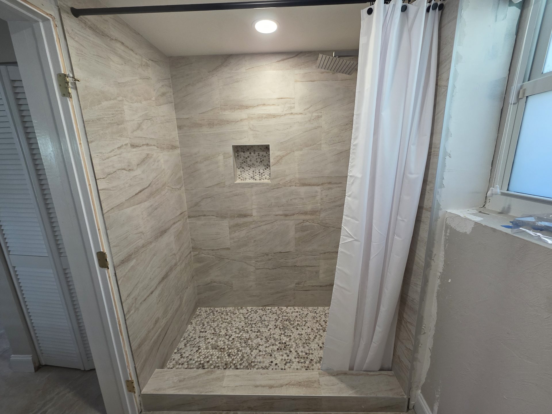 Baño remodelado por Firenova con azulejo símil piedra y nicho de ducha
